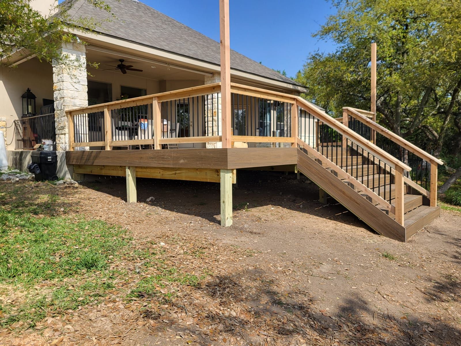 A wooden deck with stairs leading up to it is in front of a house.