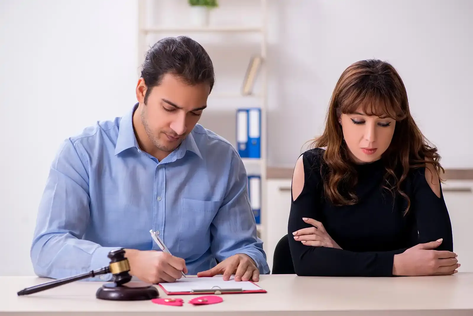 a man and a woman are sitting at a table with papers and a gavel .