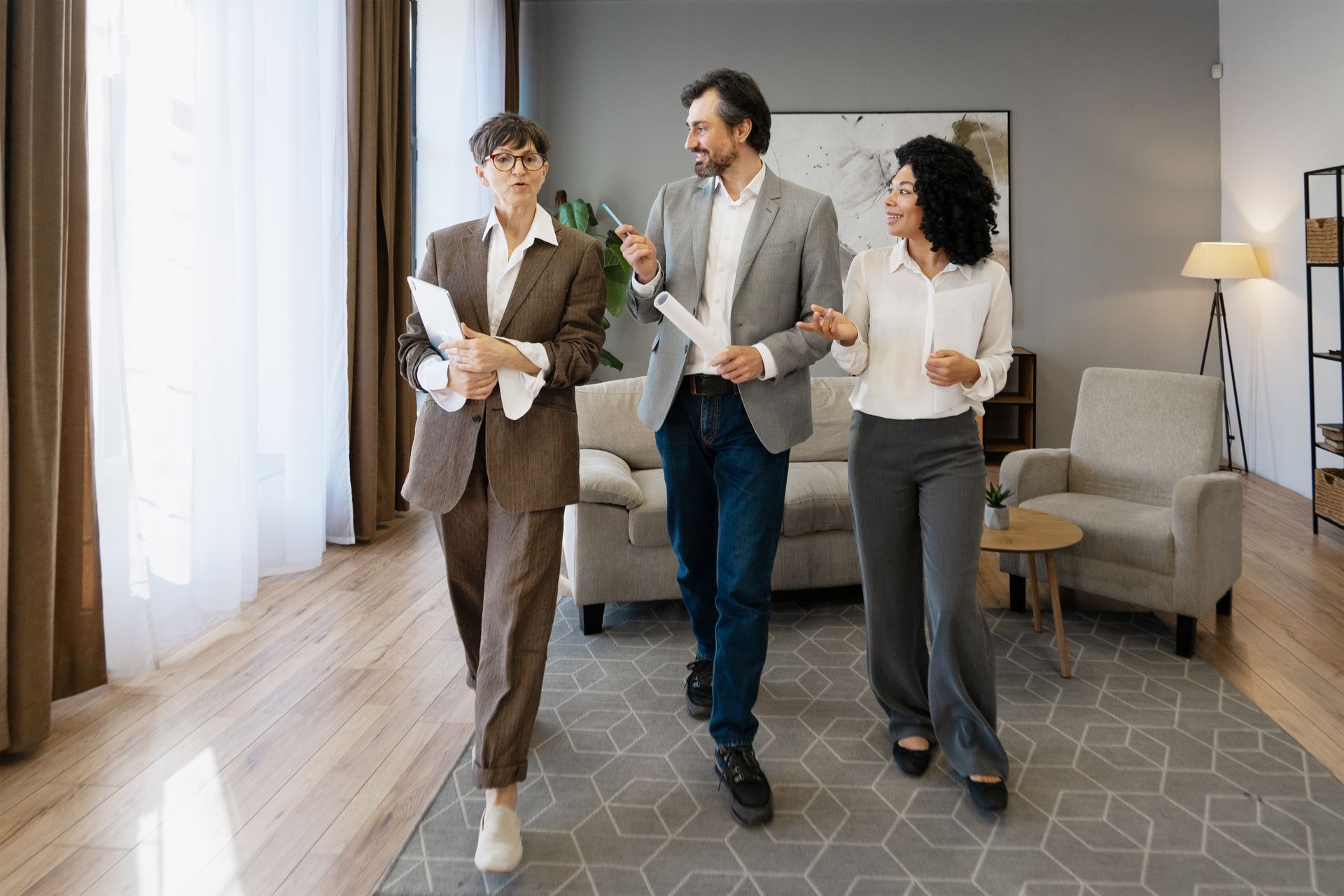 Three coworkers walking and talking in a bright office lounge holding coffee and papers