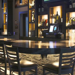 A bar with a table and chairs and bottles on shelves