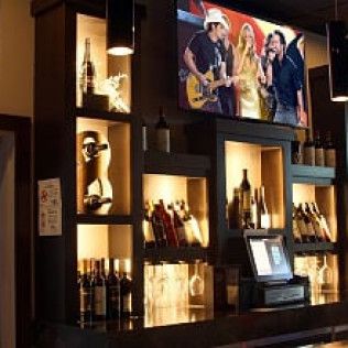 A bar with bottles of wine and a television on the wall.