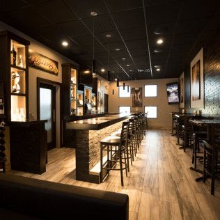 A restaurant with a long bar and tables and chairs