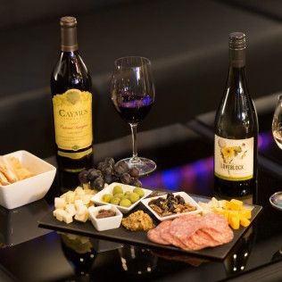 Two bottles of caymus wine are on a table with food