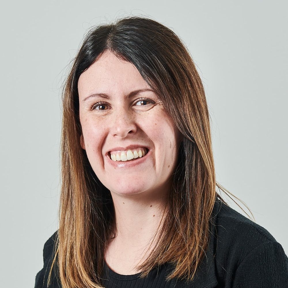 A woman with long hair is smiling and wearing a black shirt.