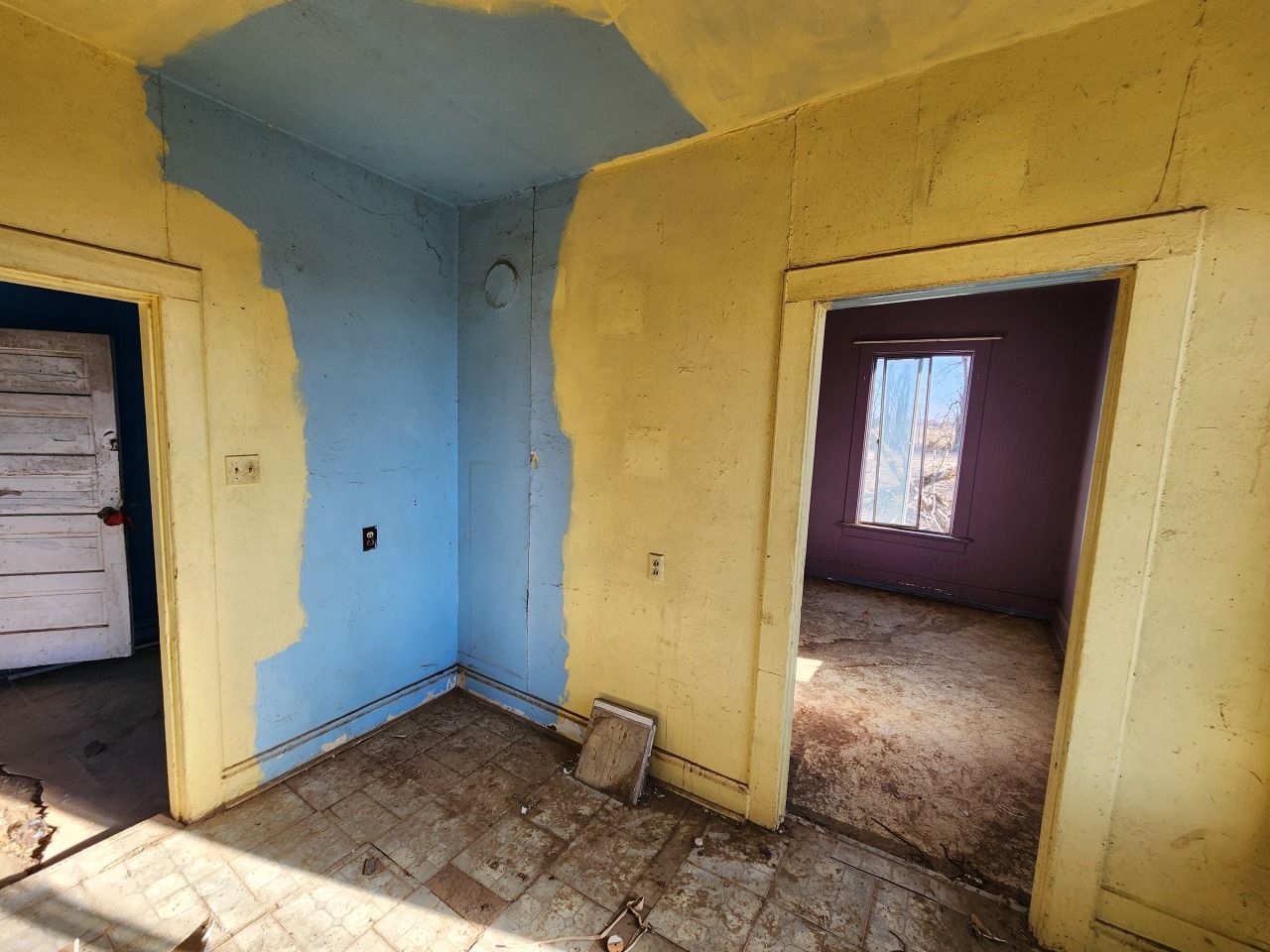 Empty room with yellow walls, blue corner, tiled floor, and two open doorways. Empty room with yellow walls, blue corner, tiled floor, and two open doorways.