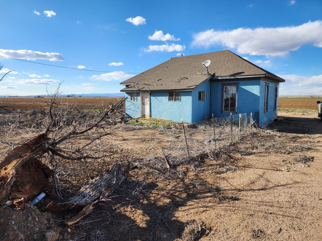 Abandoned blue house in a dry, barren field under a clear sky Abandoned blue house in a dry, barren field under a clear sky