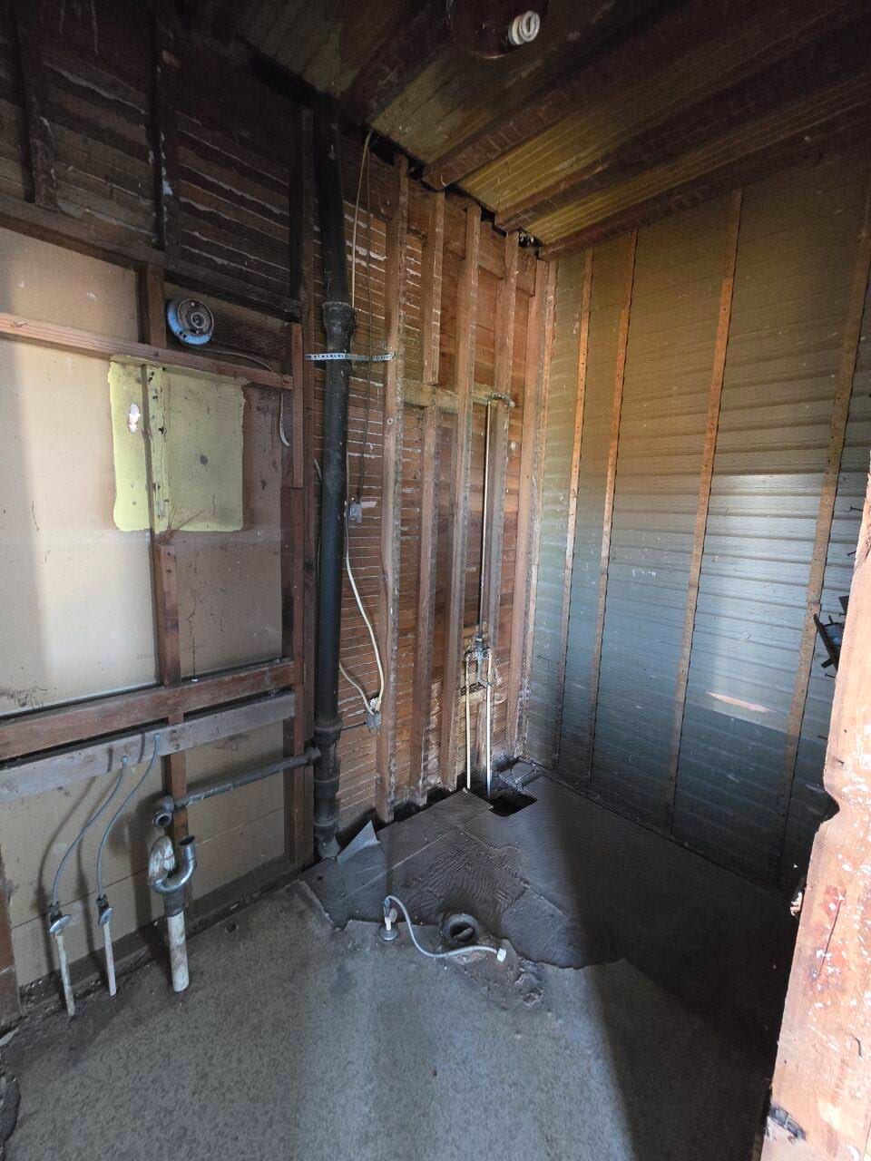 Renovation area with exposed wooden studs, pipes, and insulation in an unfinished room Renovation area with exposed wooden studs, pipes, and insulation in an unfinished room