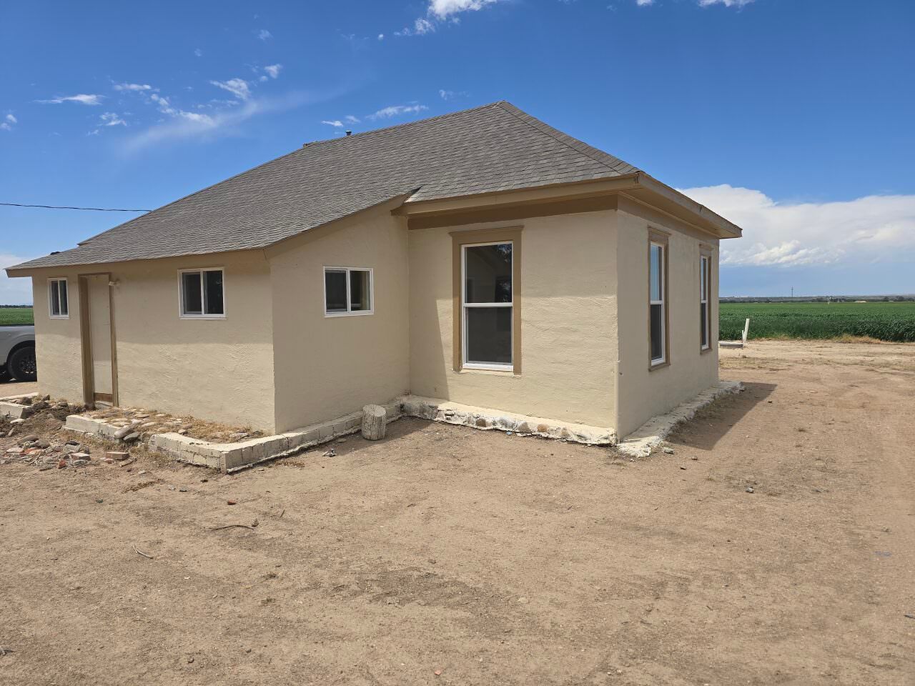 New beige house under construction on a dirt lot beneath a blue sky