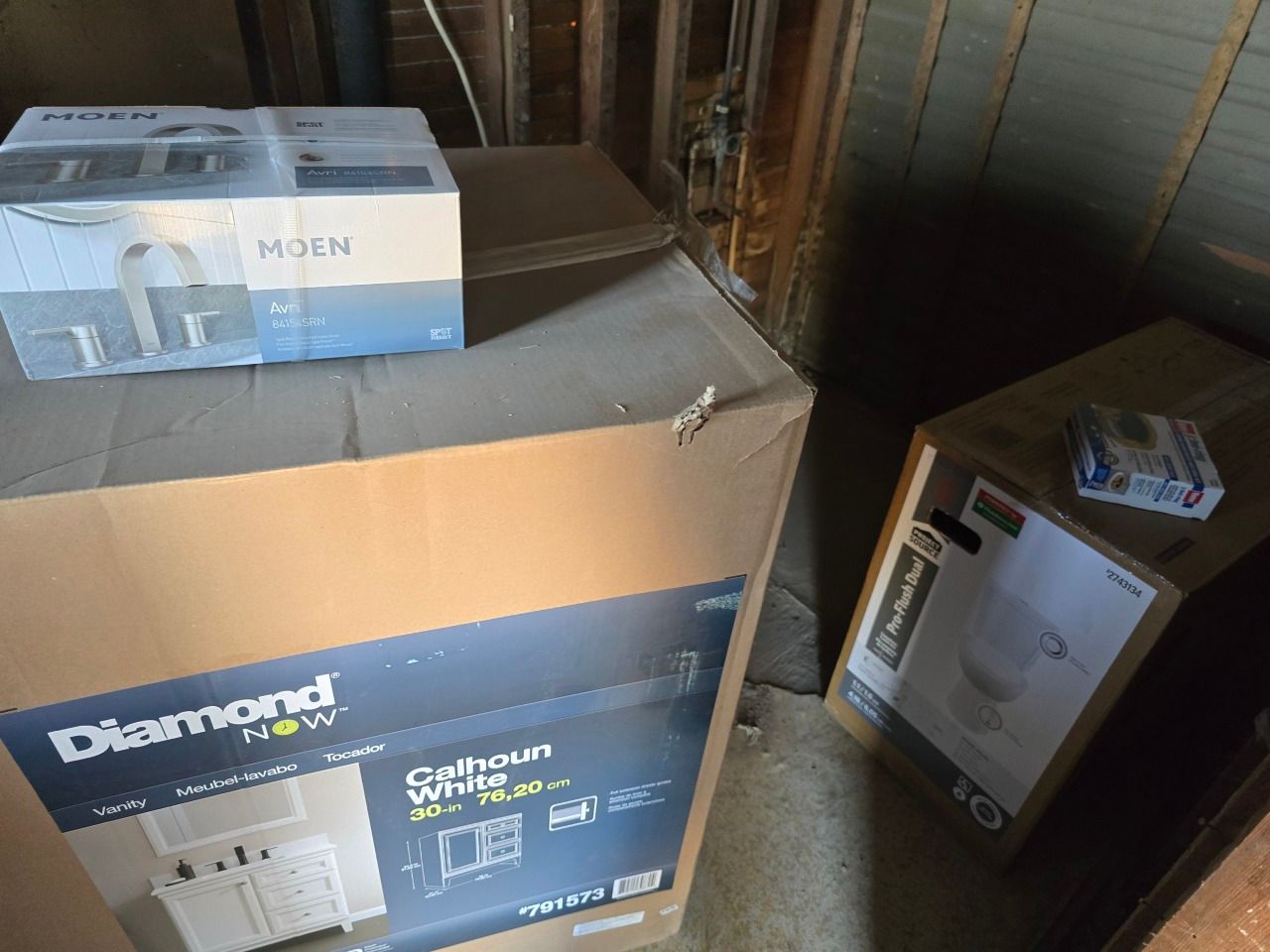 Cardboard boxes stacked in a storage area, including a Diamond pet cage box and a Moon box on top. Cardboard boxes stacked in a storage area, including a Diamond pet cage box and a Moon box on top.