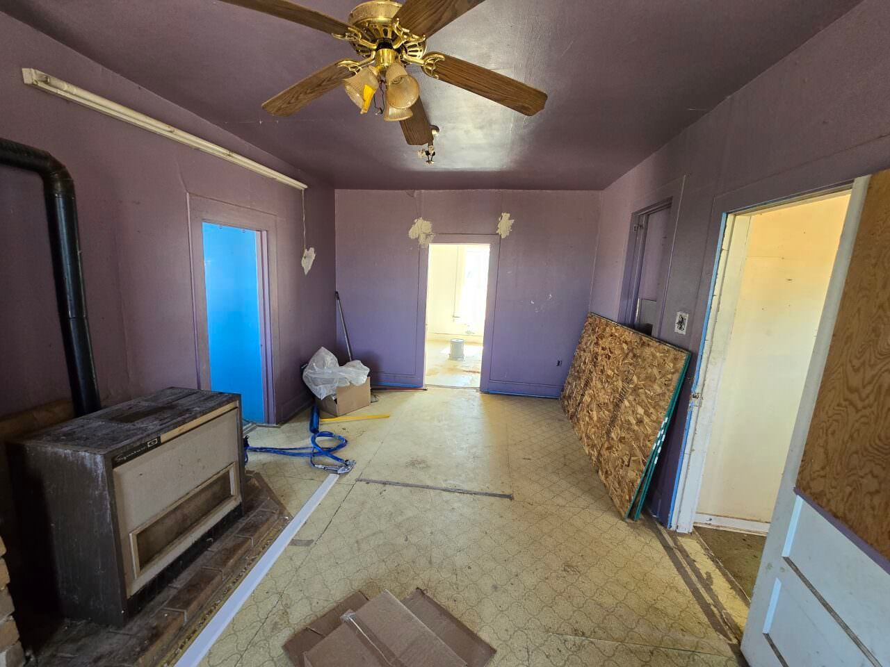 Empty lavender room with a ceiling fan, blue doors, and a window air conditioner unit.