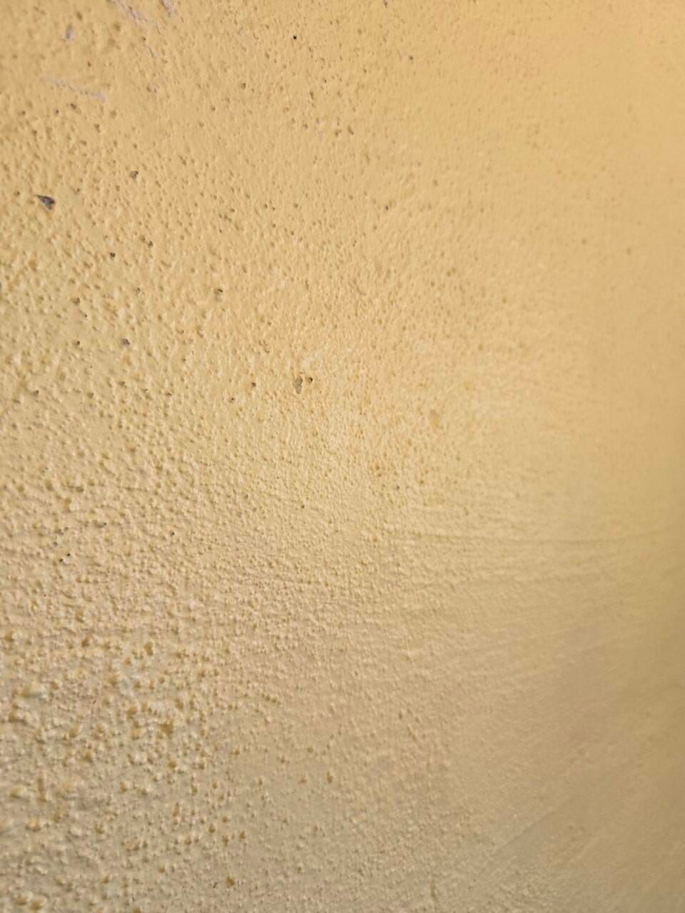 Close-up of a beige textured wall with a subtle horizontal shadow line Close-up of a beige textured wall with a subtle horizontal shadow line