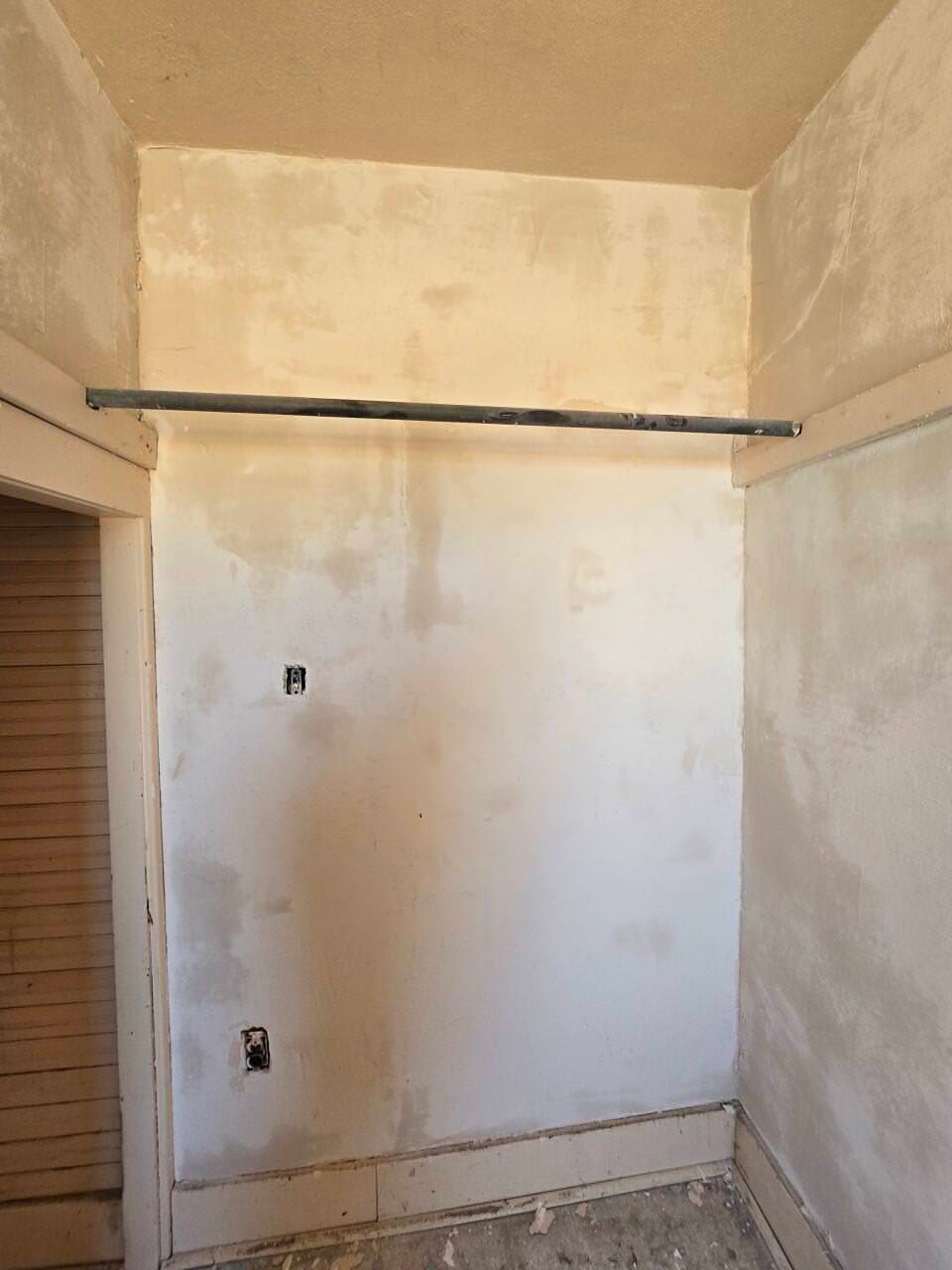 Small unfinished room with beige walls, a white panel, and exposed conduit near the ceiling. Small unfinished room with beige walls, a white panel, and exposed conduit near the ceiling.