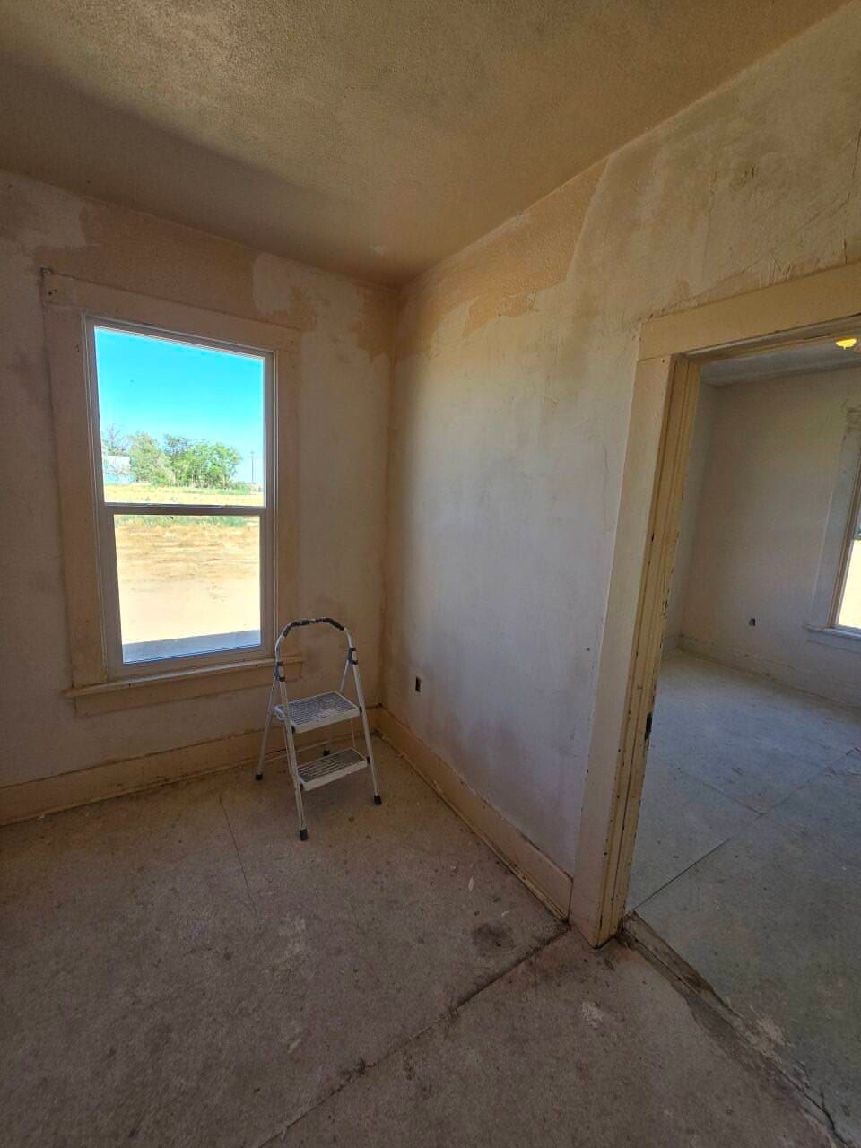 Bare room under renovation with two windows, a doorway, and a step stool on the floor. Bare room under renovation with two windows, a doorway, and a step stool on the floor.