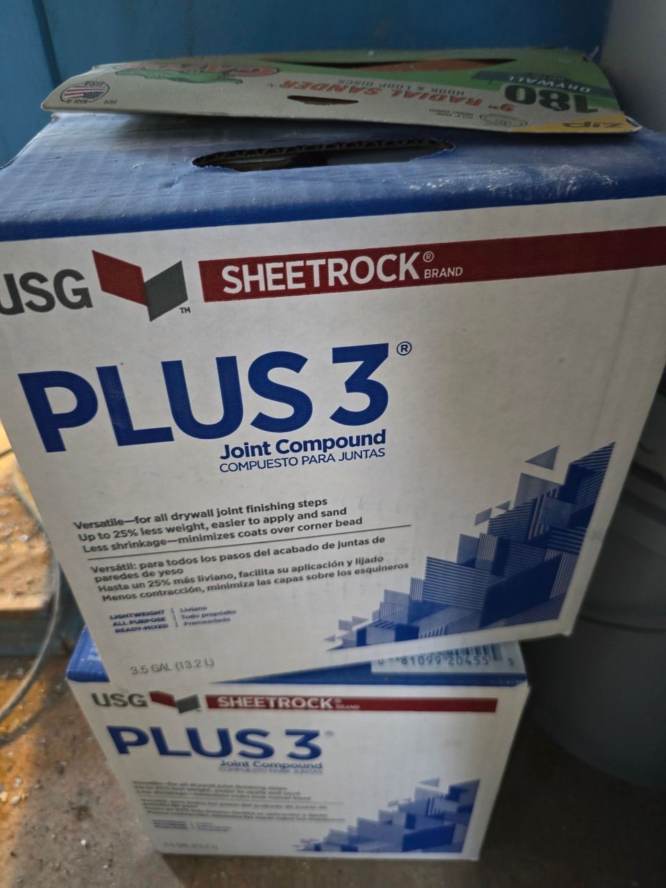 Two stacked boxes of USG Sheetrock Plus 3 joint compound with a tool on top Two stacked boxes of USG Sheetrock Plus 3 joint compound with a tool on top