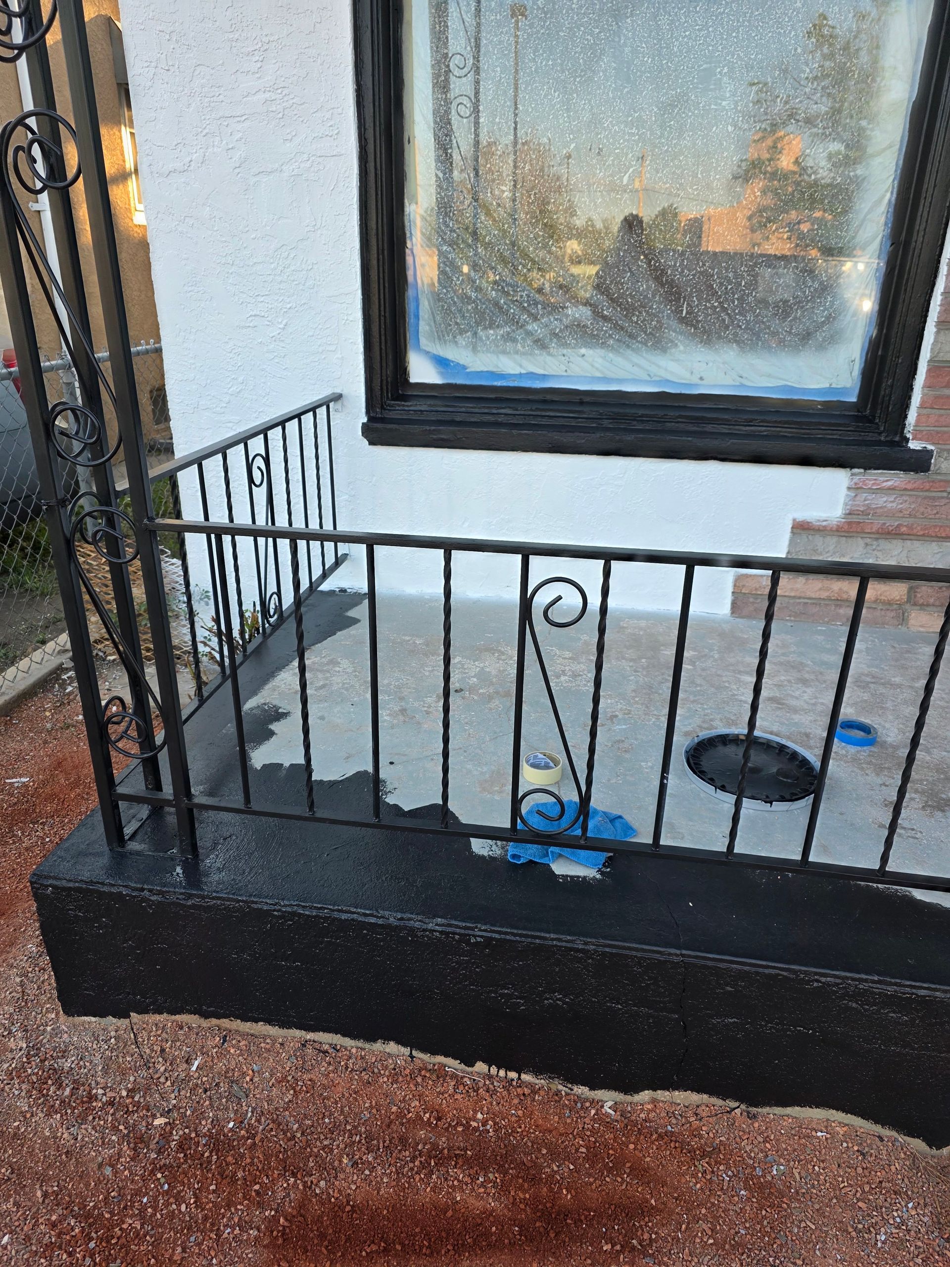 Small black front porch with metal railing, window, wet floor, and a blue toy on the ground. Small black front porch with metal railing, window, wet floor, and a blue toy on the ground.