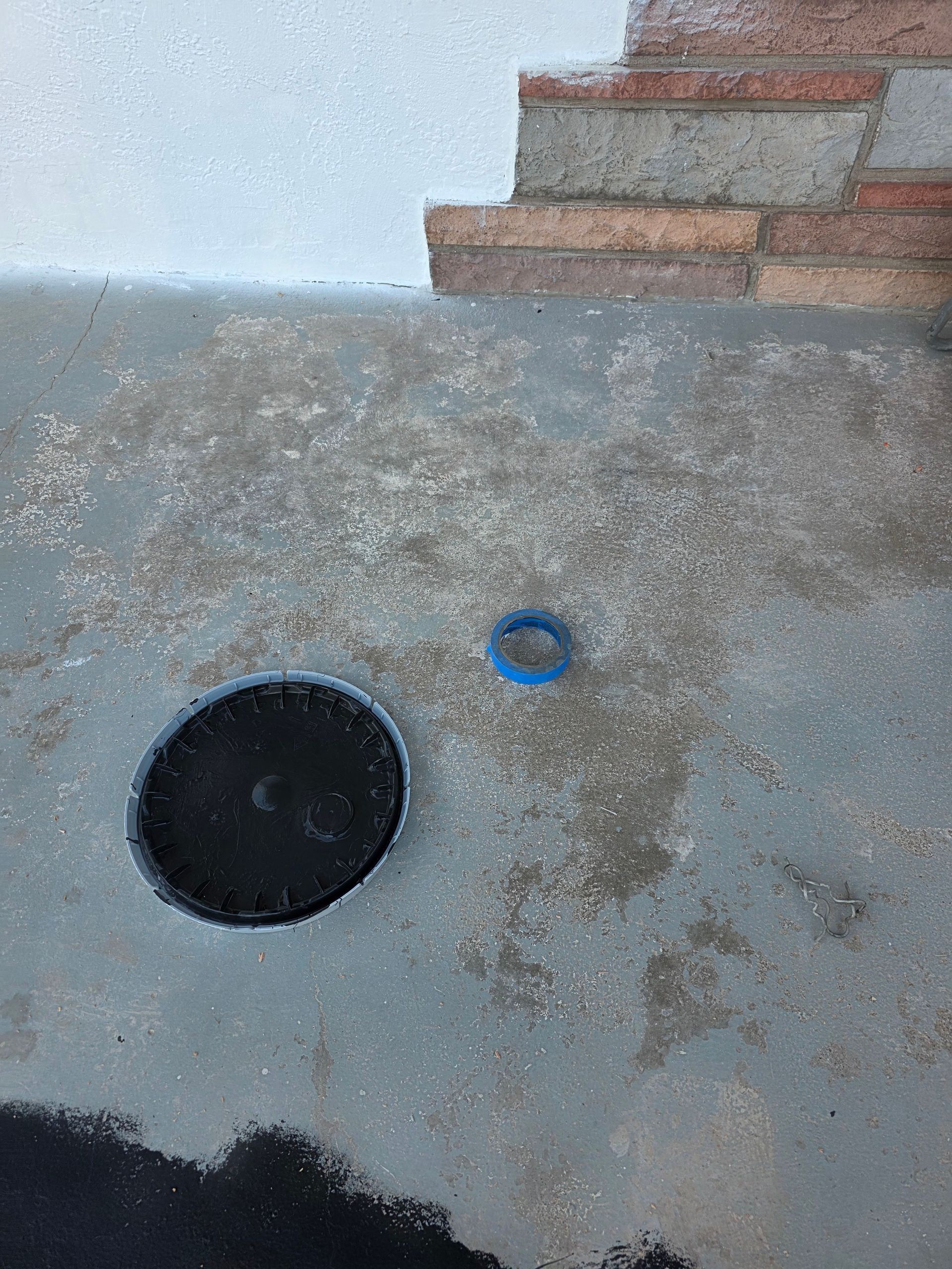 Concrete ledge with a black circular drain and a small blue ring near the top right Concrete ledge with a black circular drain and a small blue ring near the top right