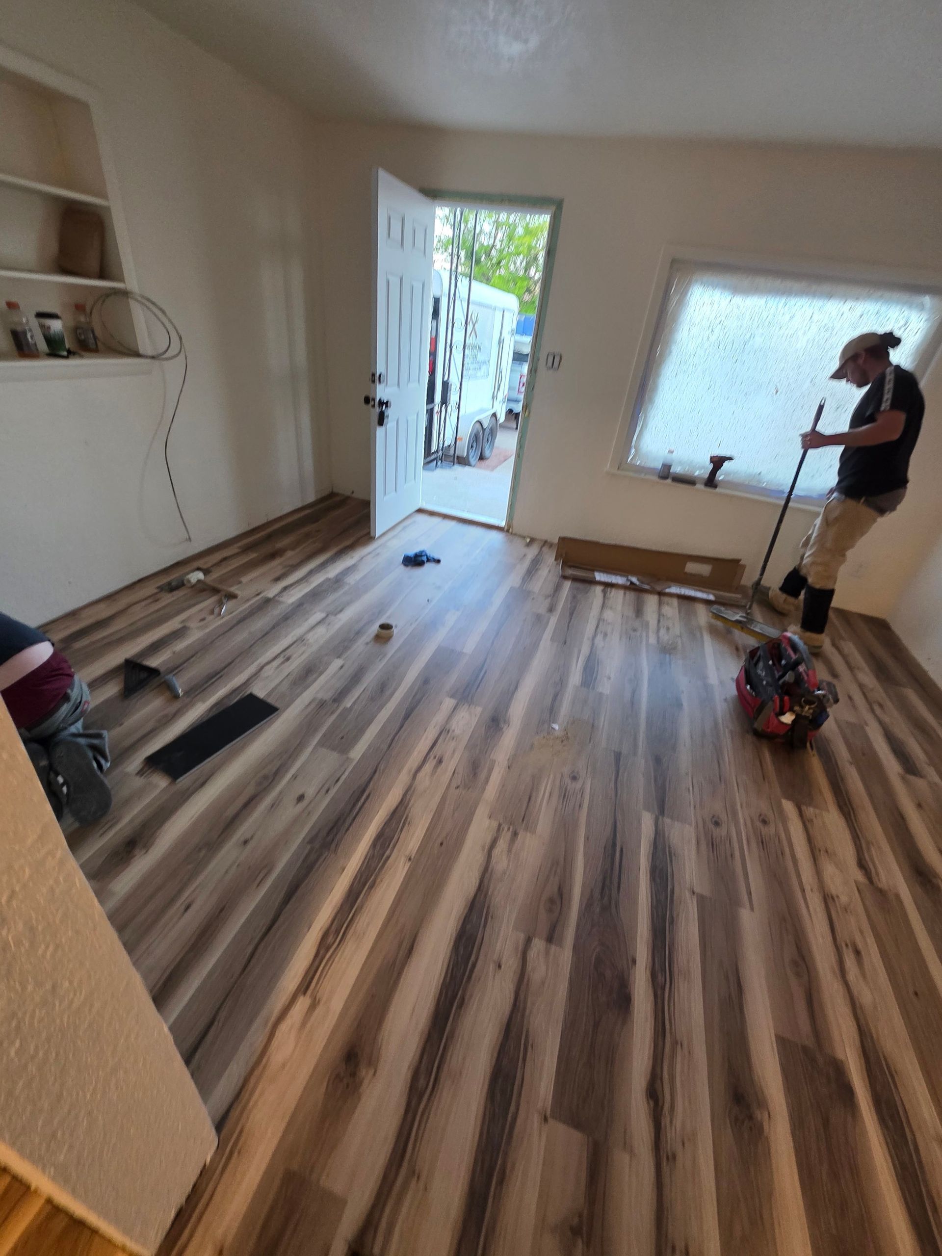 Empty room with wood floors, open door, and a person standing by a hoverboard near the wall. Empty room with wood floors, open door, and a person standing by a hoverboard near the wall.