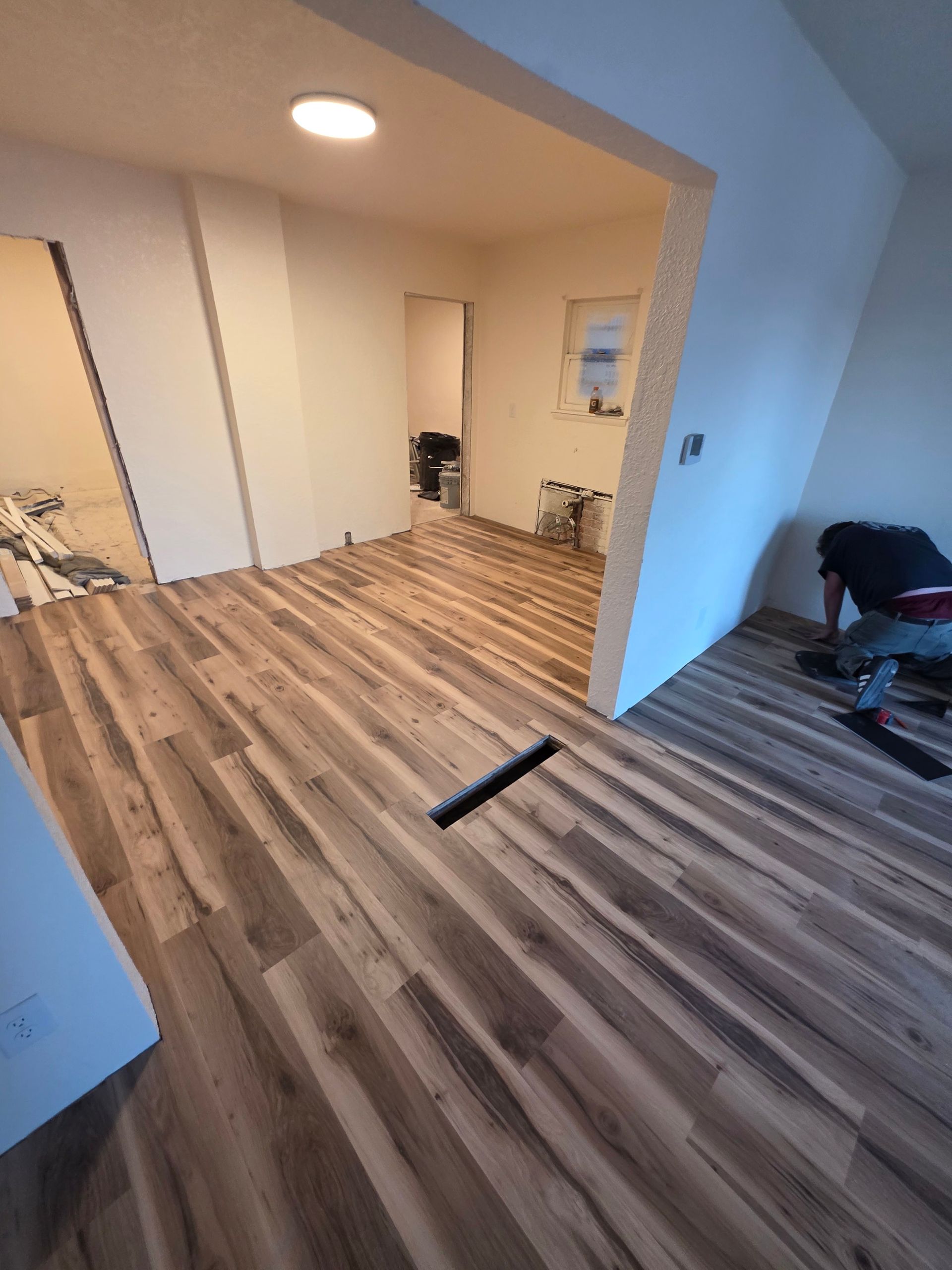 Empty room with wood flooring, white walls, and a black strip on the floor during renovation Empty room with wood flooring, white walls, and a black strip on the floor during renovation