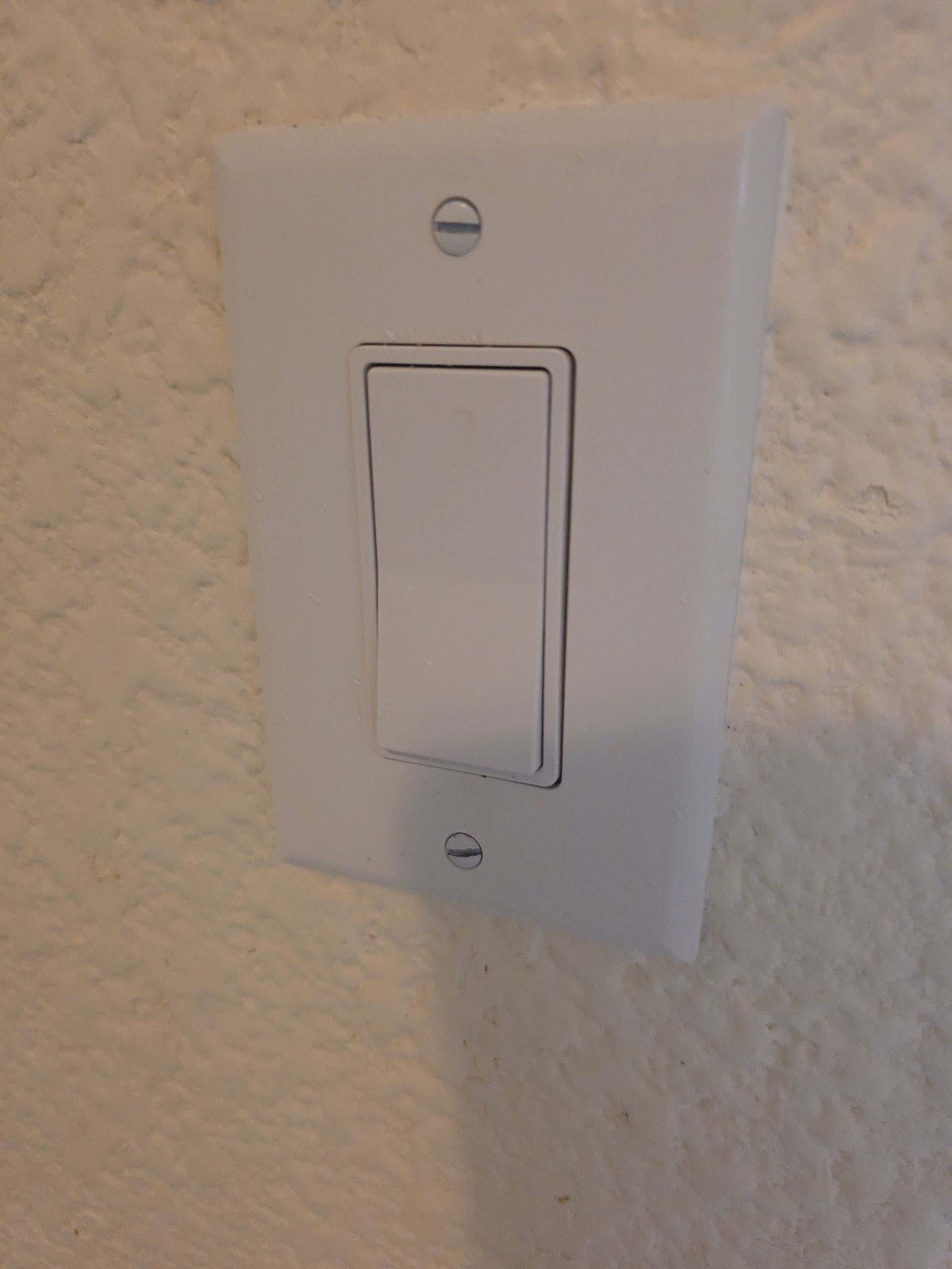 White wall light switch plate on a textured beige wall.