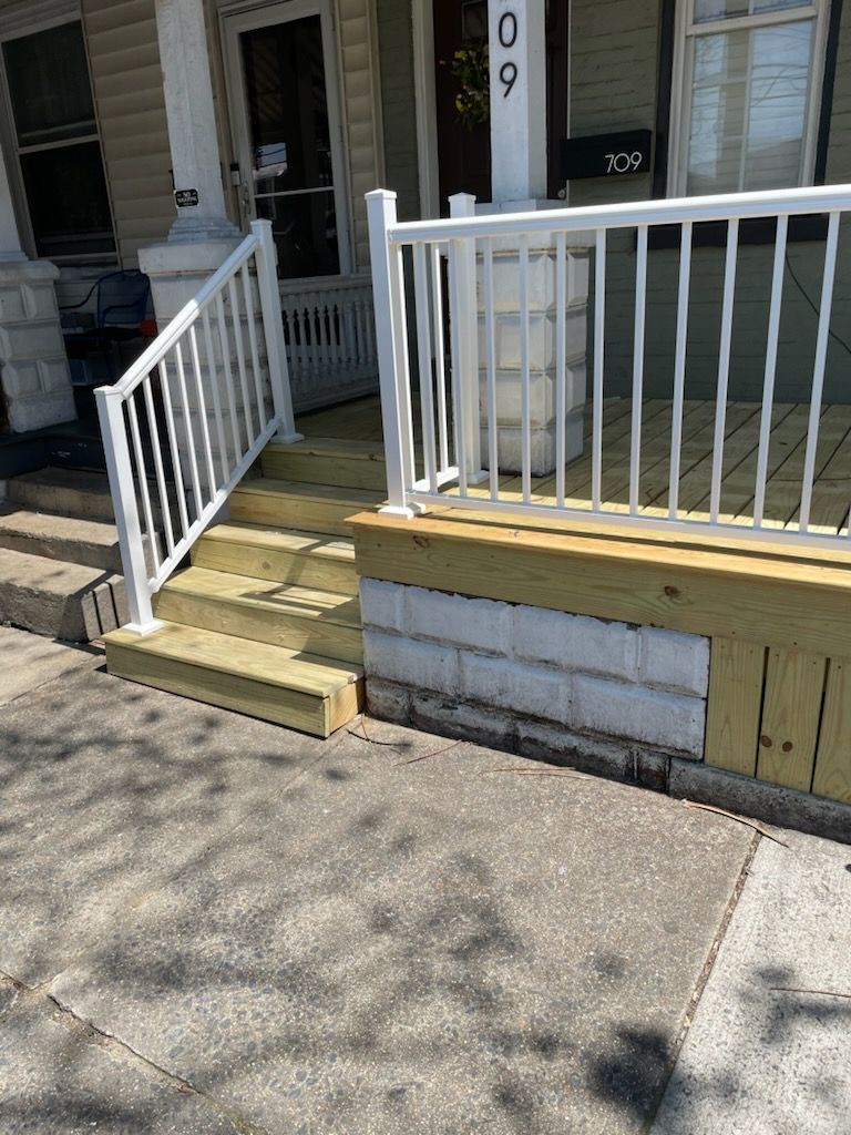 A front porch with a white railing and wooden steps.