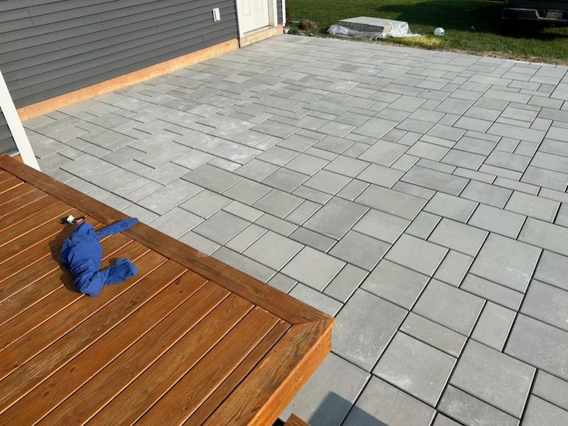 A wooden deck with a concrete patio in the background