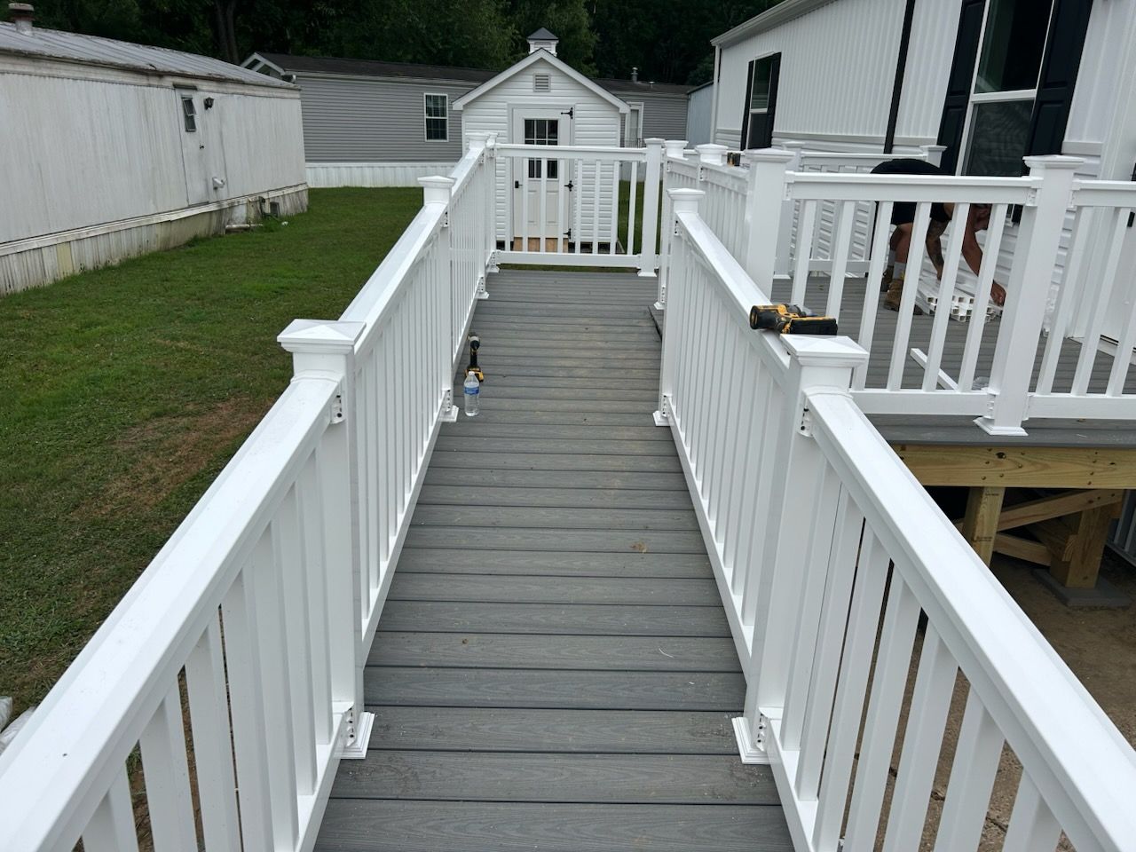 A walkway with a white railing leading to a house