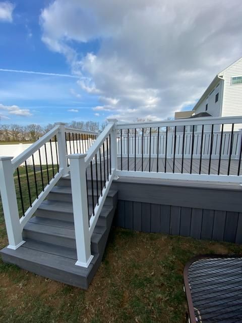A deck with stairs leading up to it and a white railing.