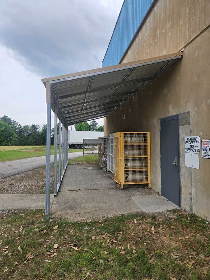 Building exterior with metal awning over a concrete area. 