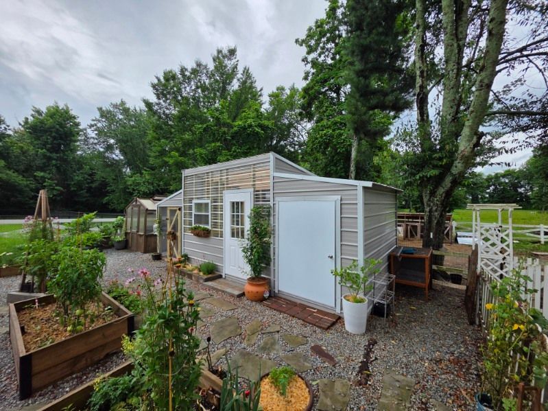 Metal sheds with gray and white siding, one with a ramp and window.