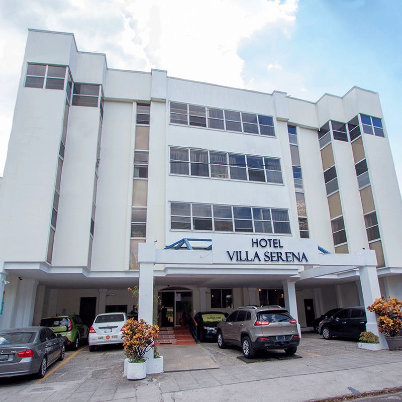 The hotel villa serena has cars parked in front of it