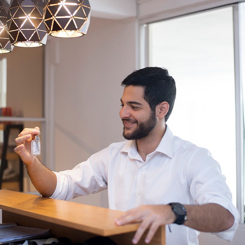 A man in a white shirt is sitting at a counter holding a key.