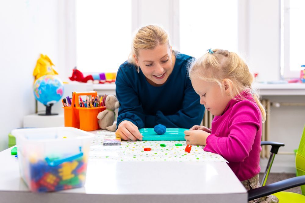 A Woman Is Playing With A Little Girl At A Table — The Therapists Cairns In Cairns City, QLD