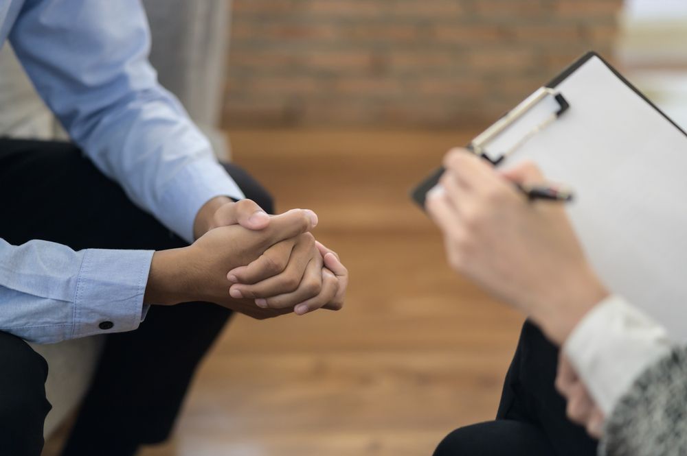 A Man And Woman Are Shaking Hands While A Woman Holds A Clipboard — The Therapists Cairns In Cairns City, QLD