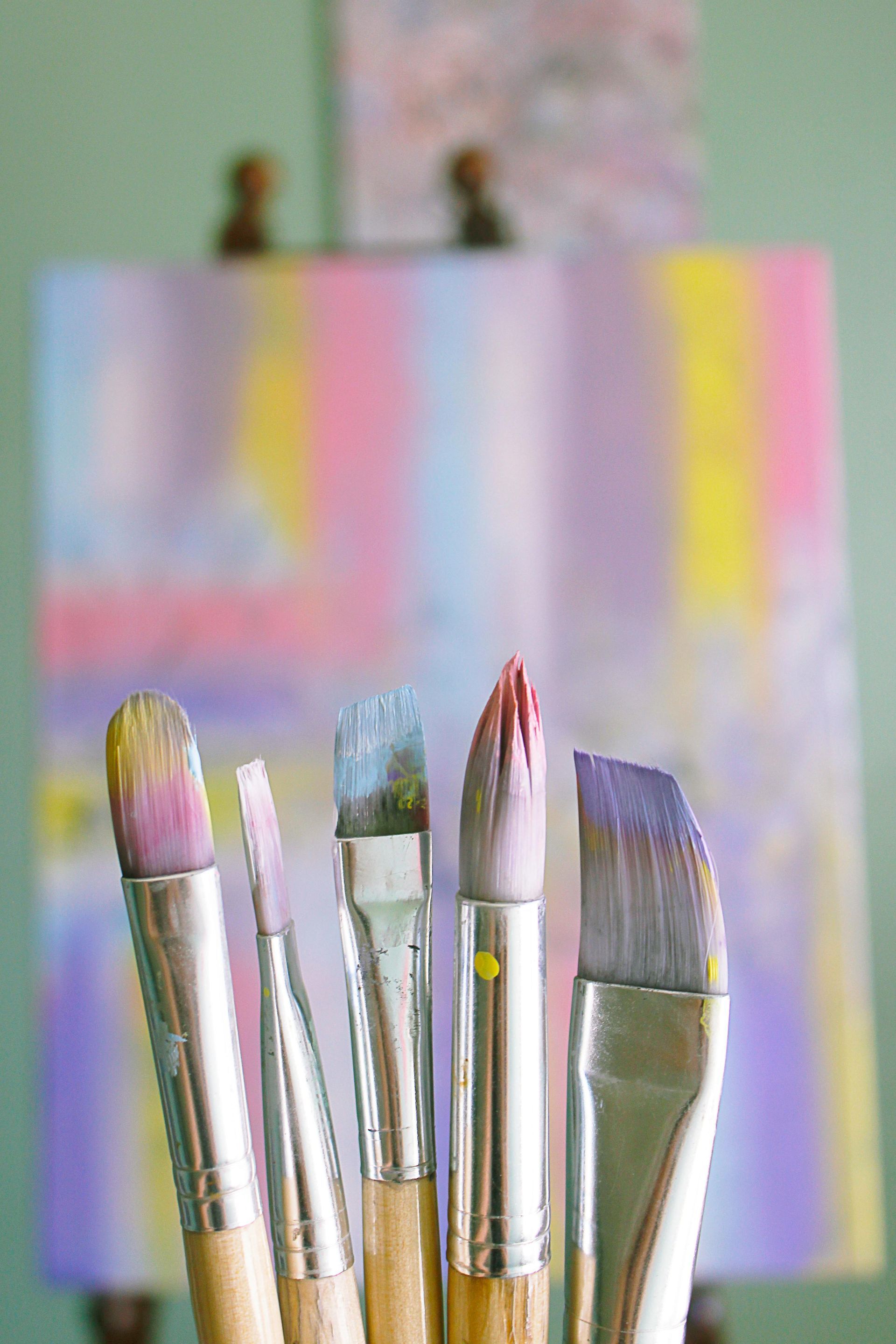 A Bunch Of Paint Brushes Are Sitting In Front Of A Painting On An Easel — The Therapists Cairns In Cairns City, QLD