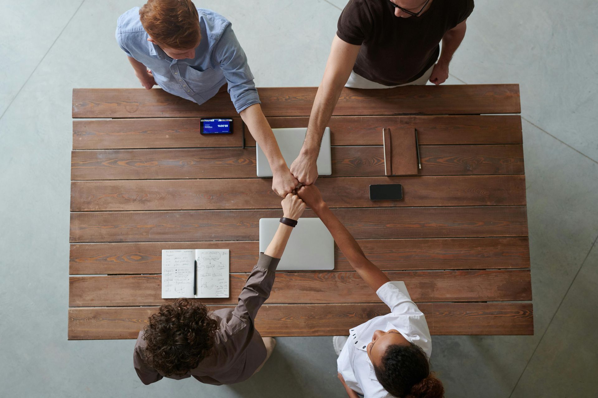A Group Of People Are Sitting At A Table Shaking Hands — The Therapists Cairns In Cairns City, QLD