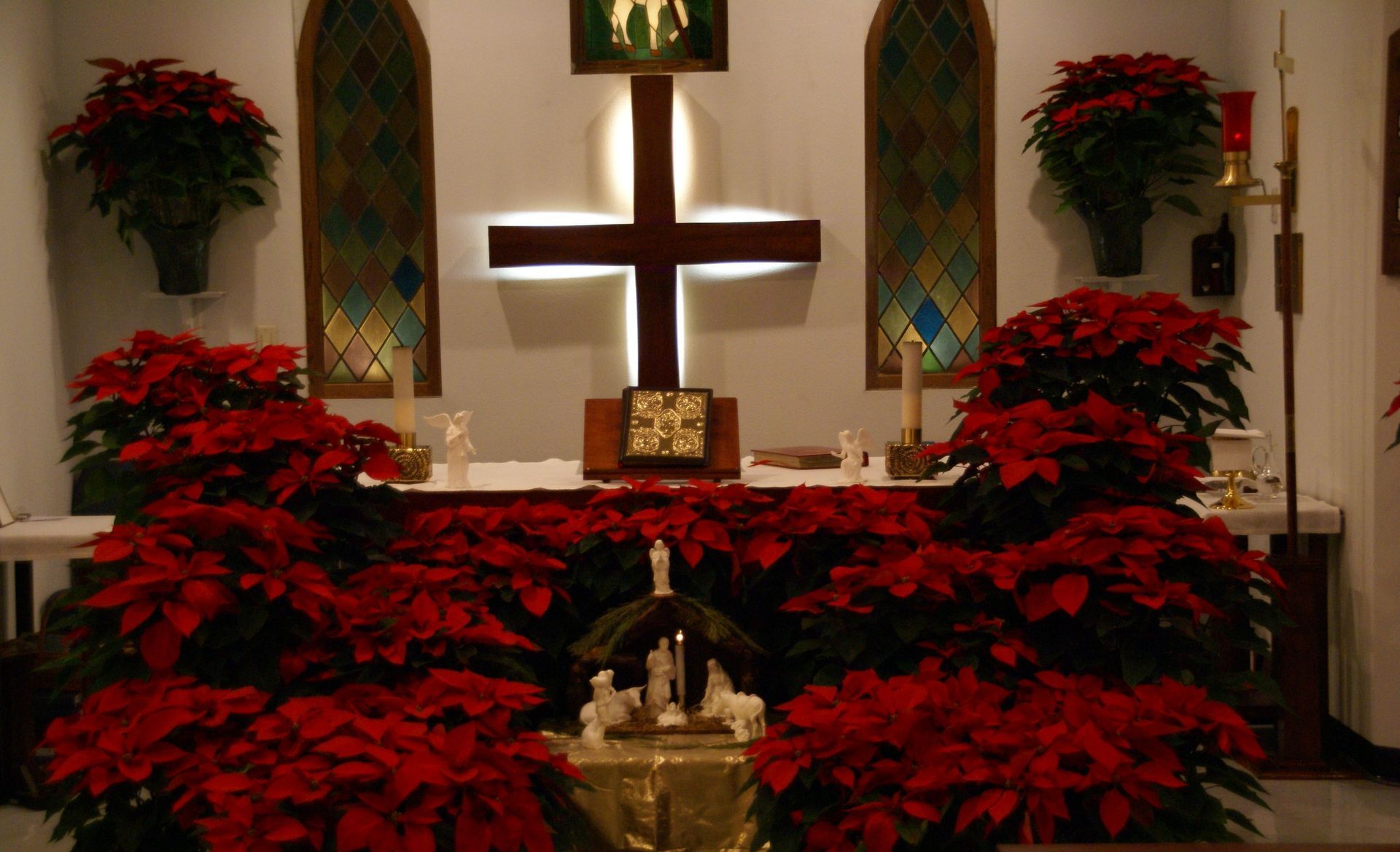 A church decorated for christmas with red flowers and a cross