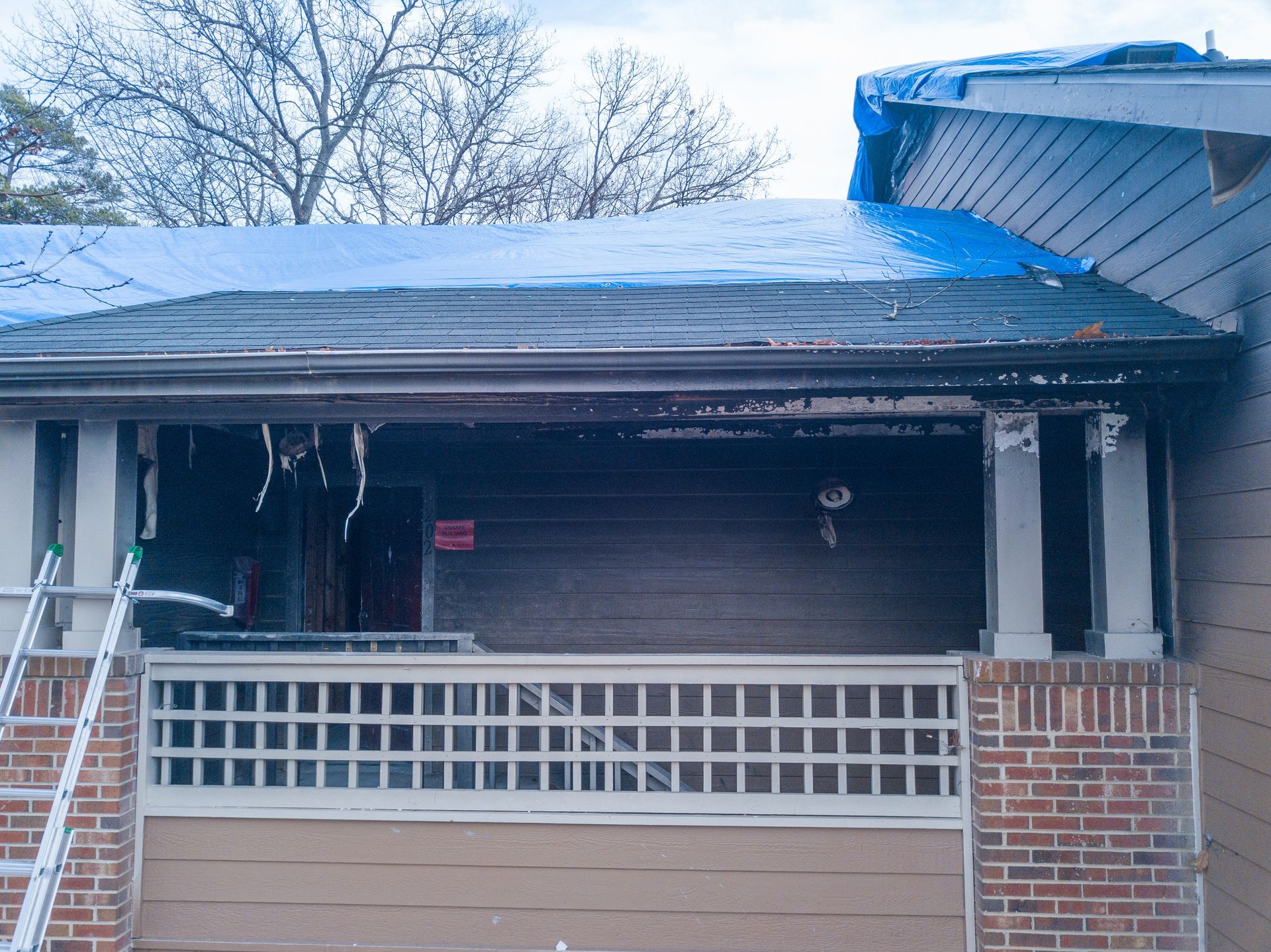 Severely fire-damaged apartment building with charred exterior and extensive structural destruction.