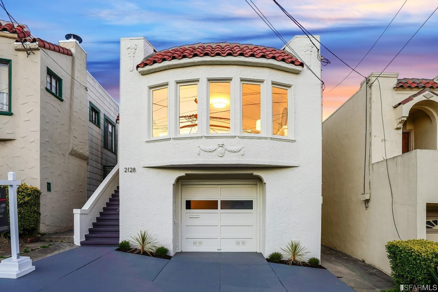 A white house with a red tile roof is for sale