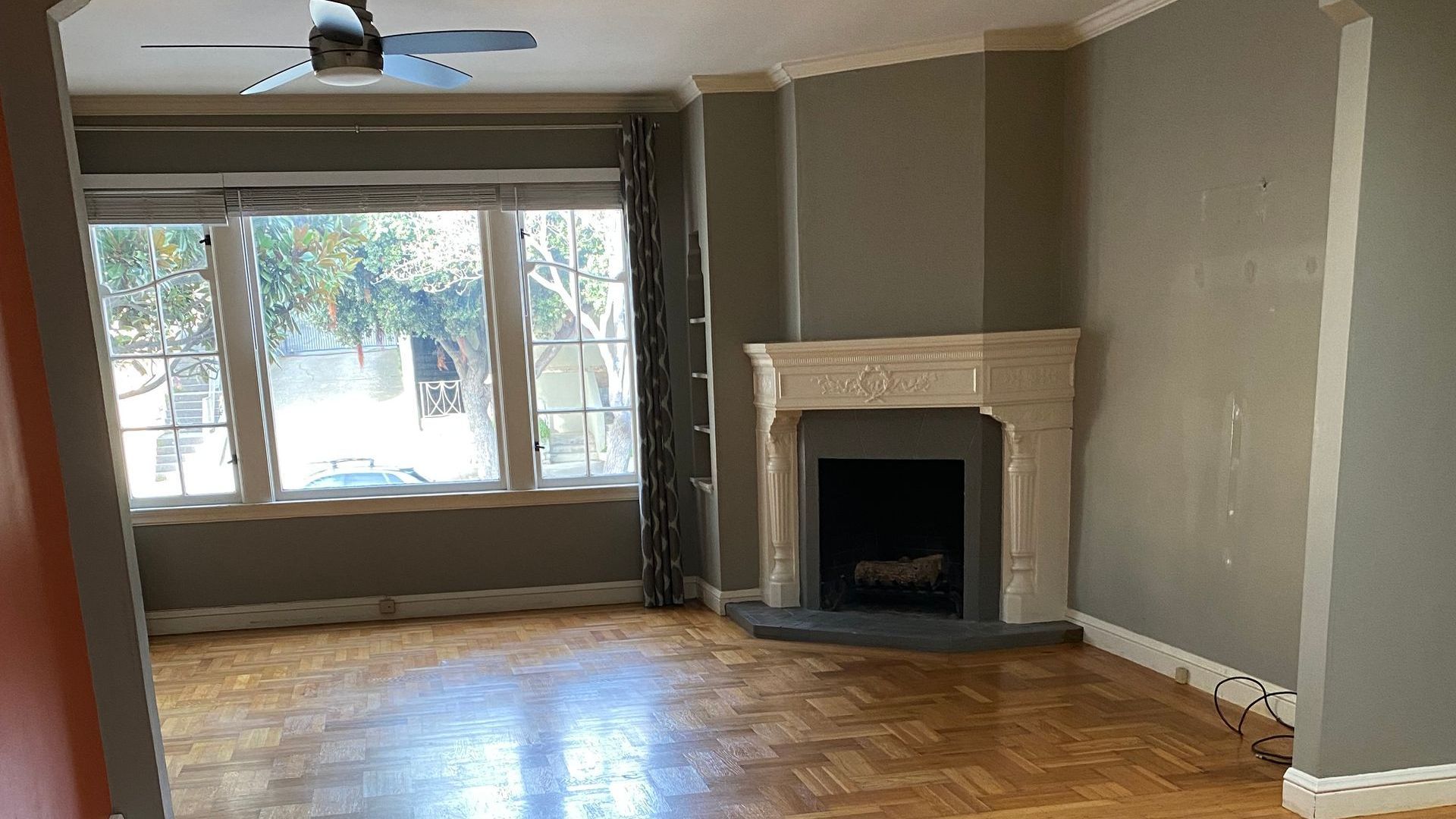 An empty living room with a fireplace and a ceiling fan.
