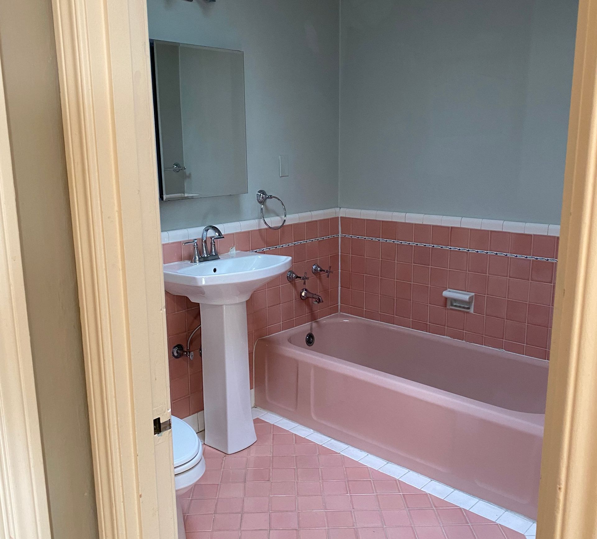 A bathroom with pink tiles and a sink and bathtub