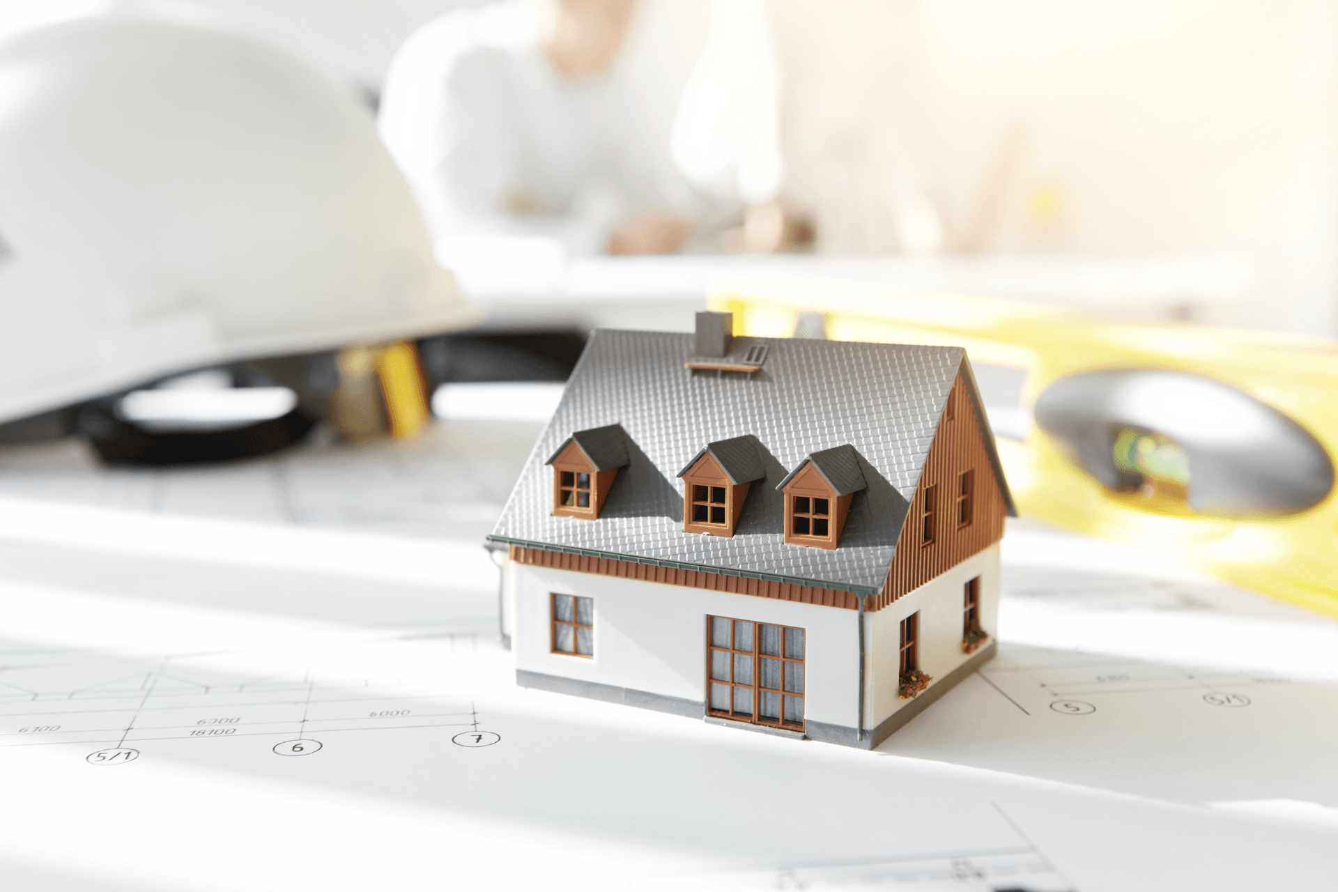 A small model house is sitting on top of a blueprint.