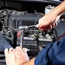 A mechanic uses a chrome ratchet to work on the engine components of a vehicle.