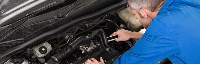 A mechanic in a blue uniform repairing a car engine.