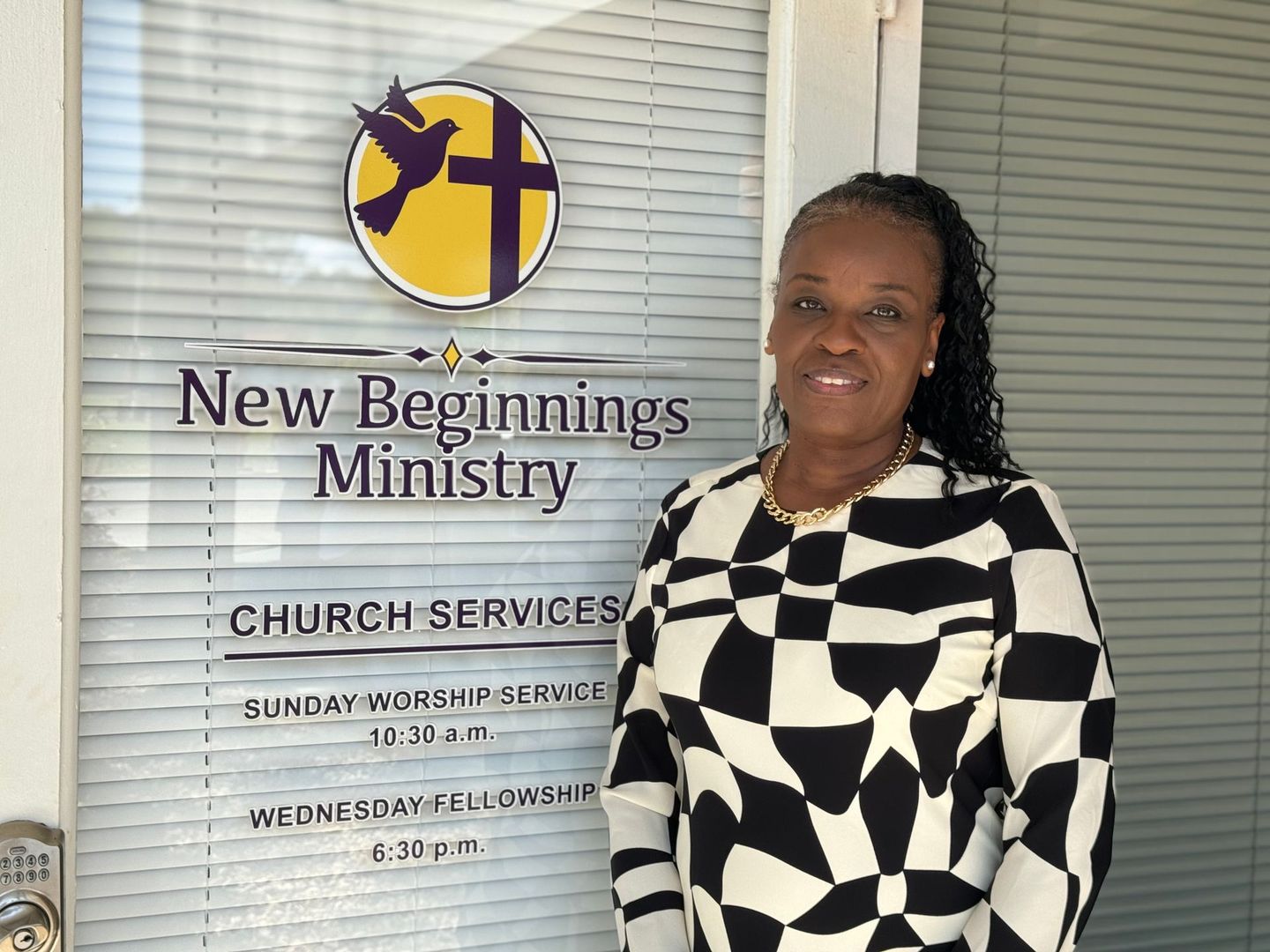 Woman standing beside New Beginnings Ministry sign and church service hours display