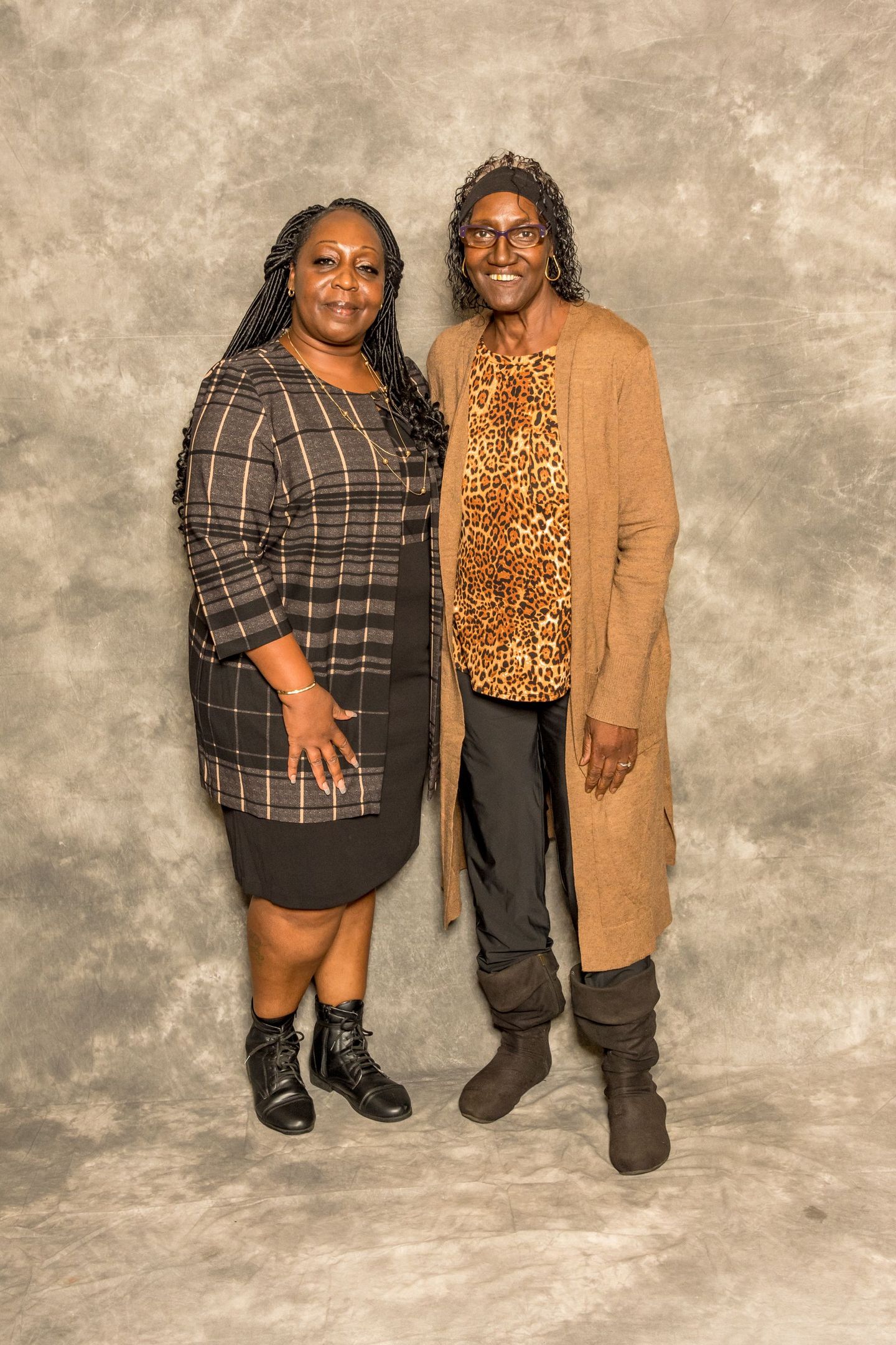 Two people standing side by side against a mottled backdrop, smiling at the camera.