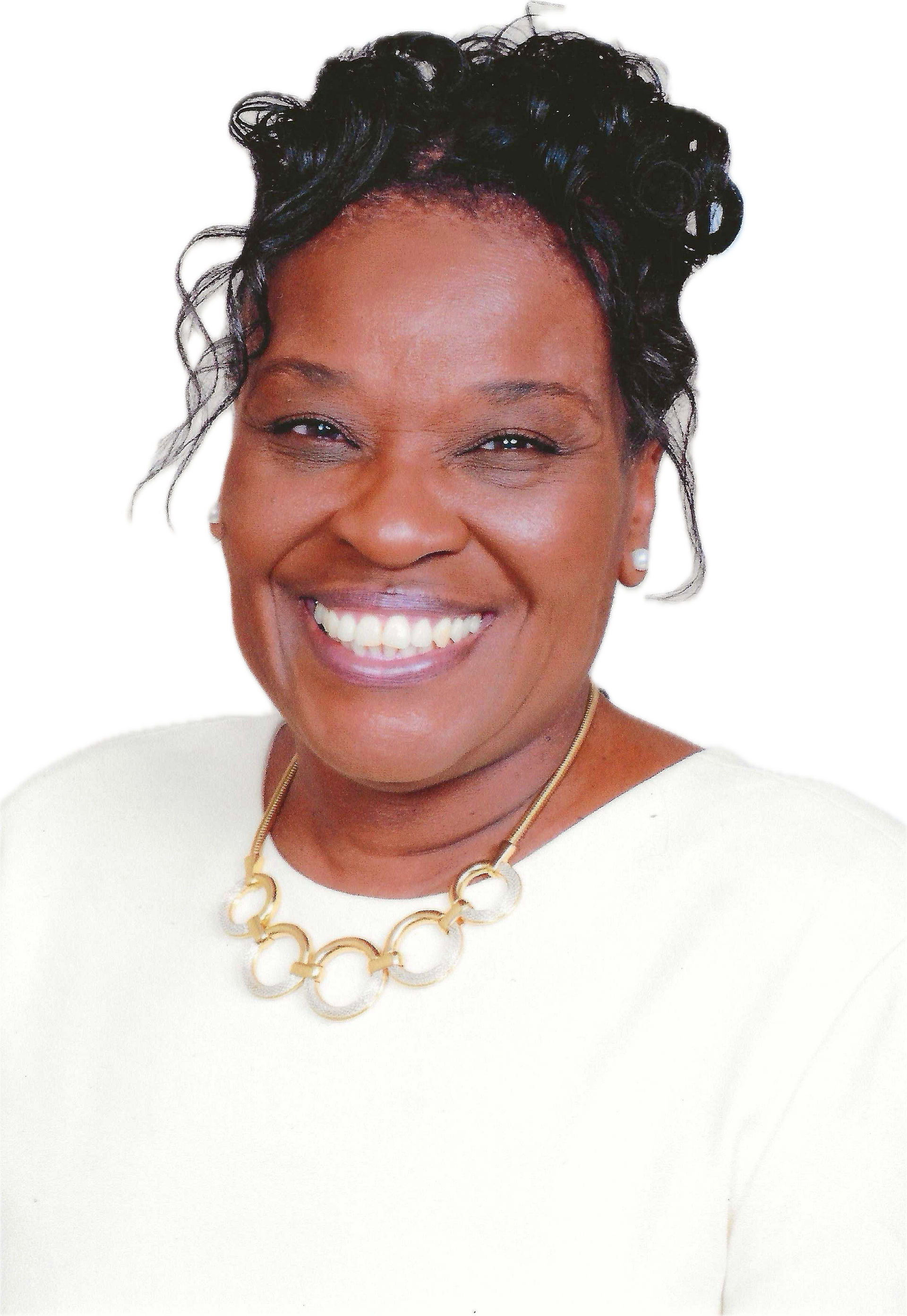 Smiling woman in a white top and gold necklace against a white background