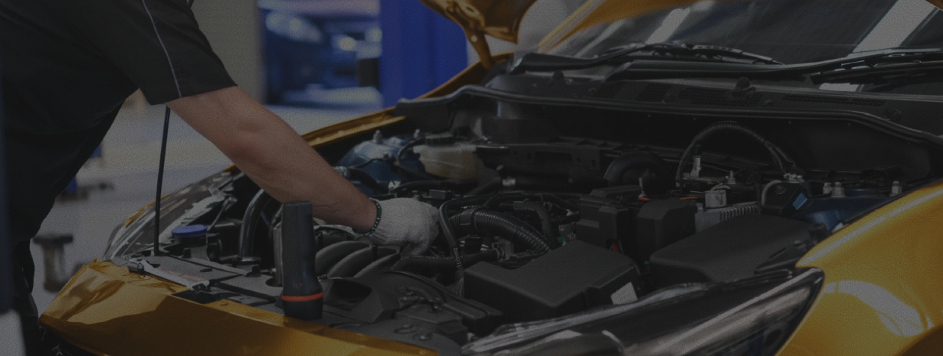 Person inspecting a car engine with the hood open in a garage | The Family Mechanics - Cherry Hill