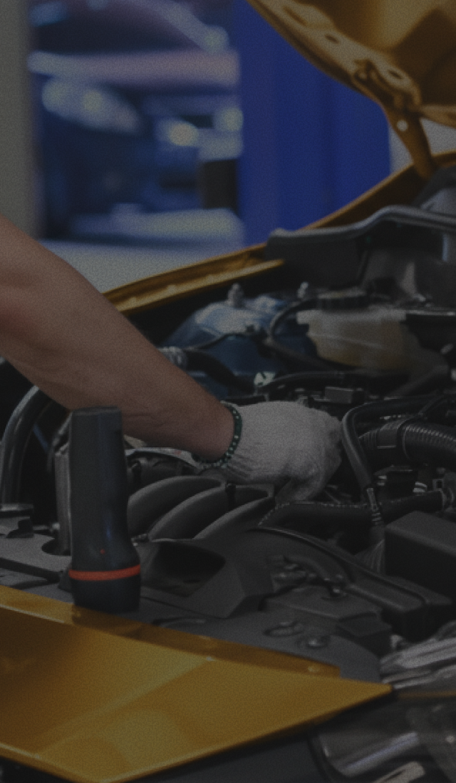 Mechanic’s gloved hands working on a yellow car engine in a garage | The Family Mechanics - Cherry Hill