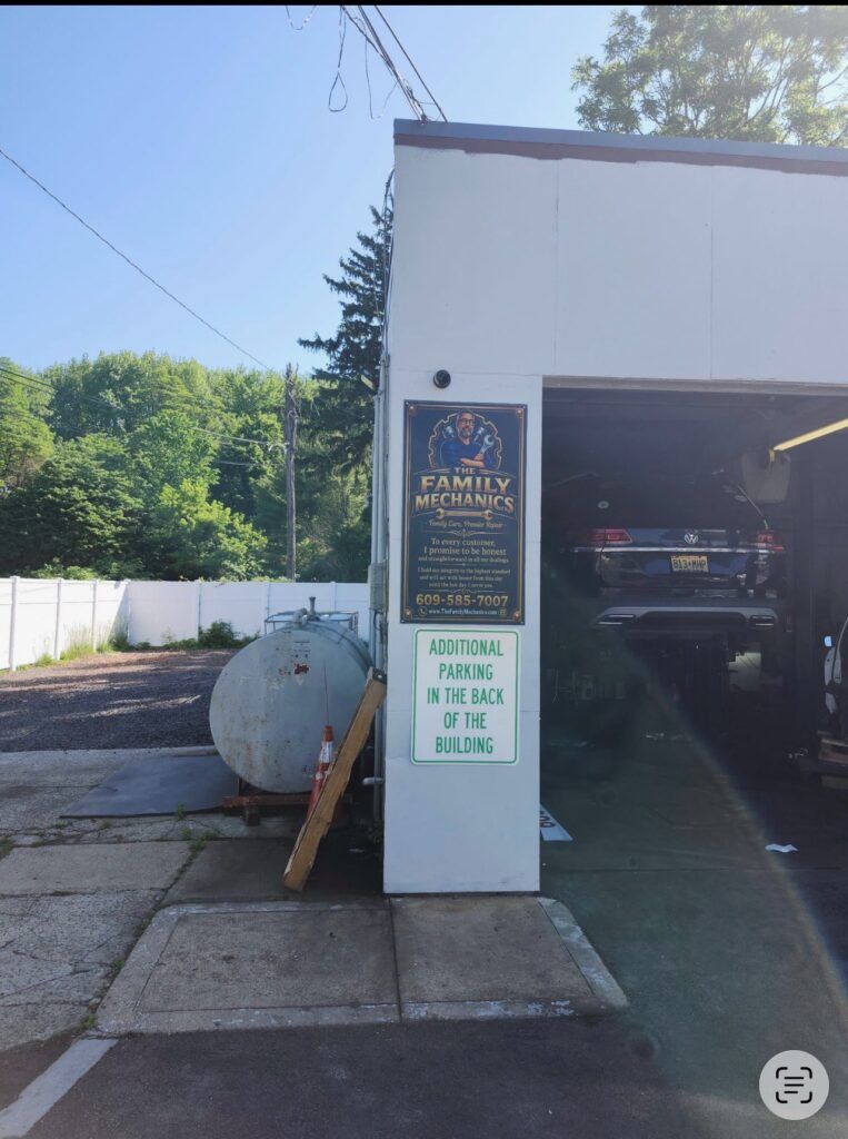 Car wash garage entrance with sign, white building, and parked vehicle inside | The Family Mechanics - Cherry Hill