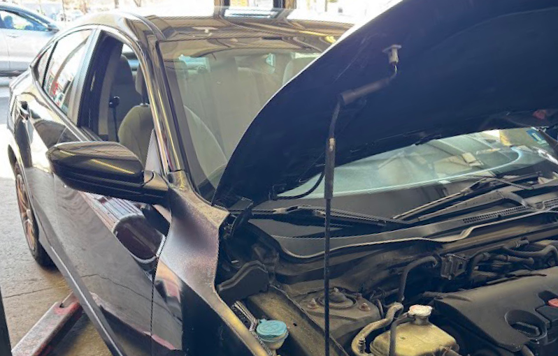 Black sedan in a garage with hood open, exposing the engine bay | The Family Mechanics - Cherry Hill
